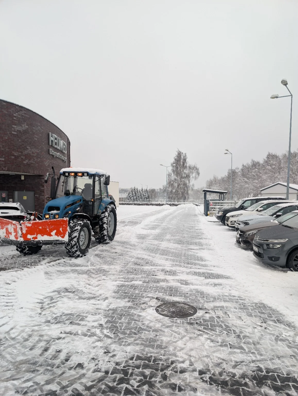 Ciągnik z pługiem na zaśnieżonym parkingu